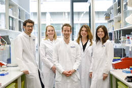 Gruppenfoto von Menschen in weißen Kitteln im Labor