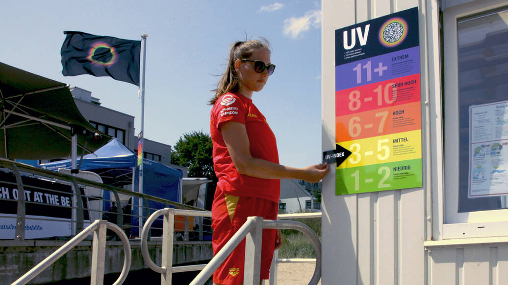 Hinweistafel zum UV-Index mit Sun Safety Flag im Hintergrund (Foto: Deutsche Krebshilfe/Vladimir Krug)