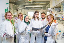 Gruppenbild im Labor mit der jungen Ärztin Dr. Laura Hinze und weiteren Personen in weißen Kitteln
