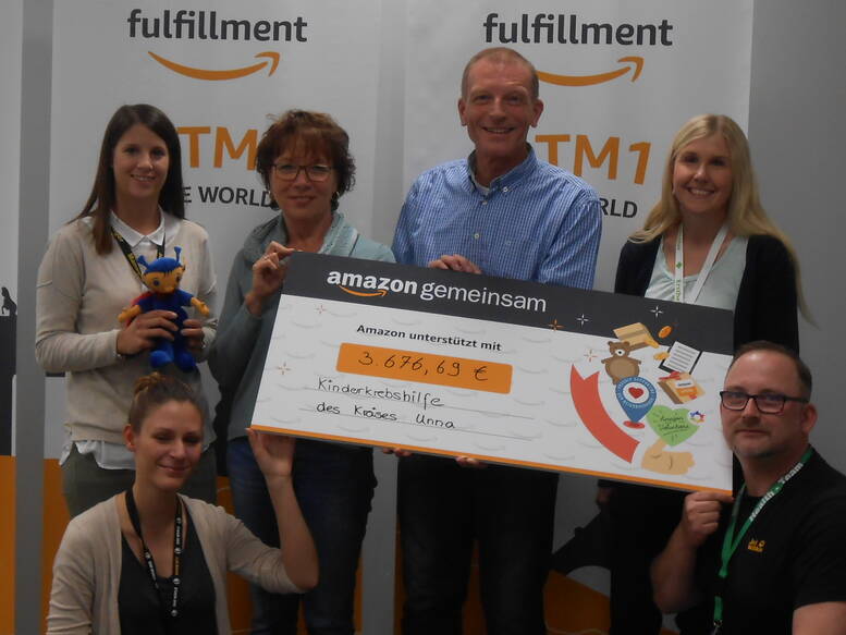 Die Mitarbeiterinnen und Mitarbeiter von Amazon Werne freuen sich gemeinsam mit Monika und Dieter Rebbert (Mitte), langjährigen Unterstützern der Deutschen KinderKrebshilfe, über die erfolgreiche Aktion.